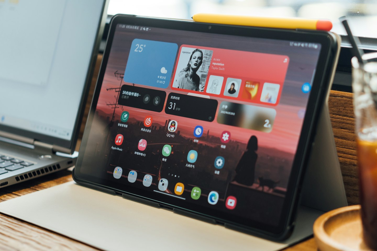 Obok laptopa i kawy leży tablet z aplikacjami.